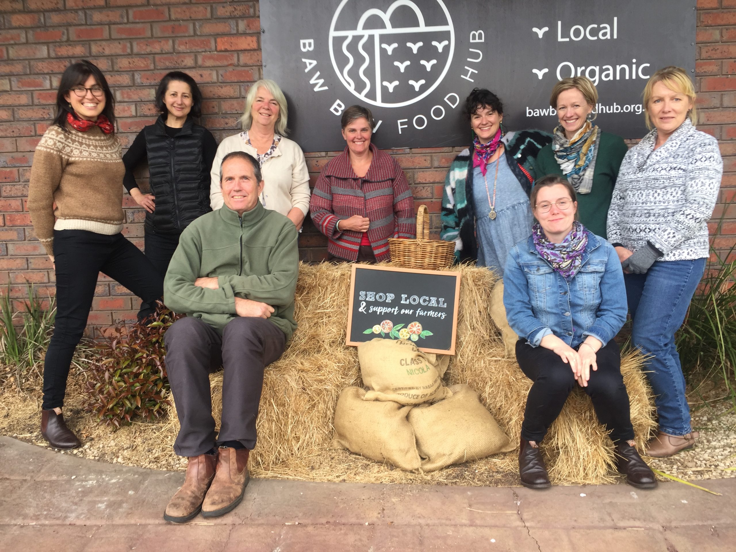 a group of people with hay bales in front of a sign for baw baw food hub